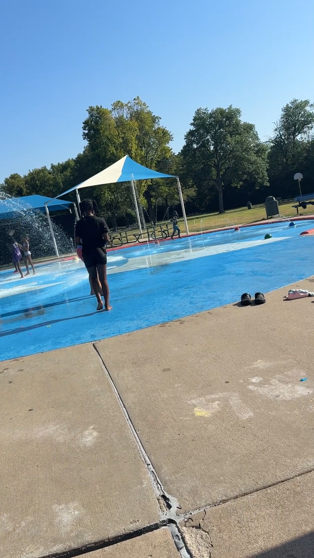 A volunteer walking the splash pad while children play