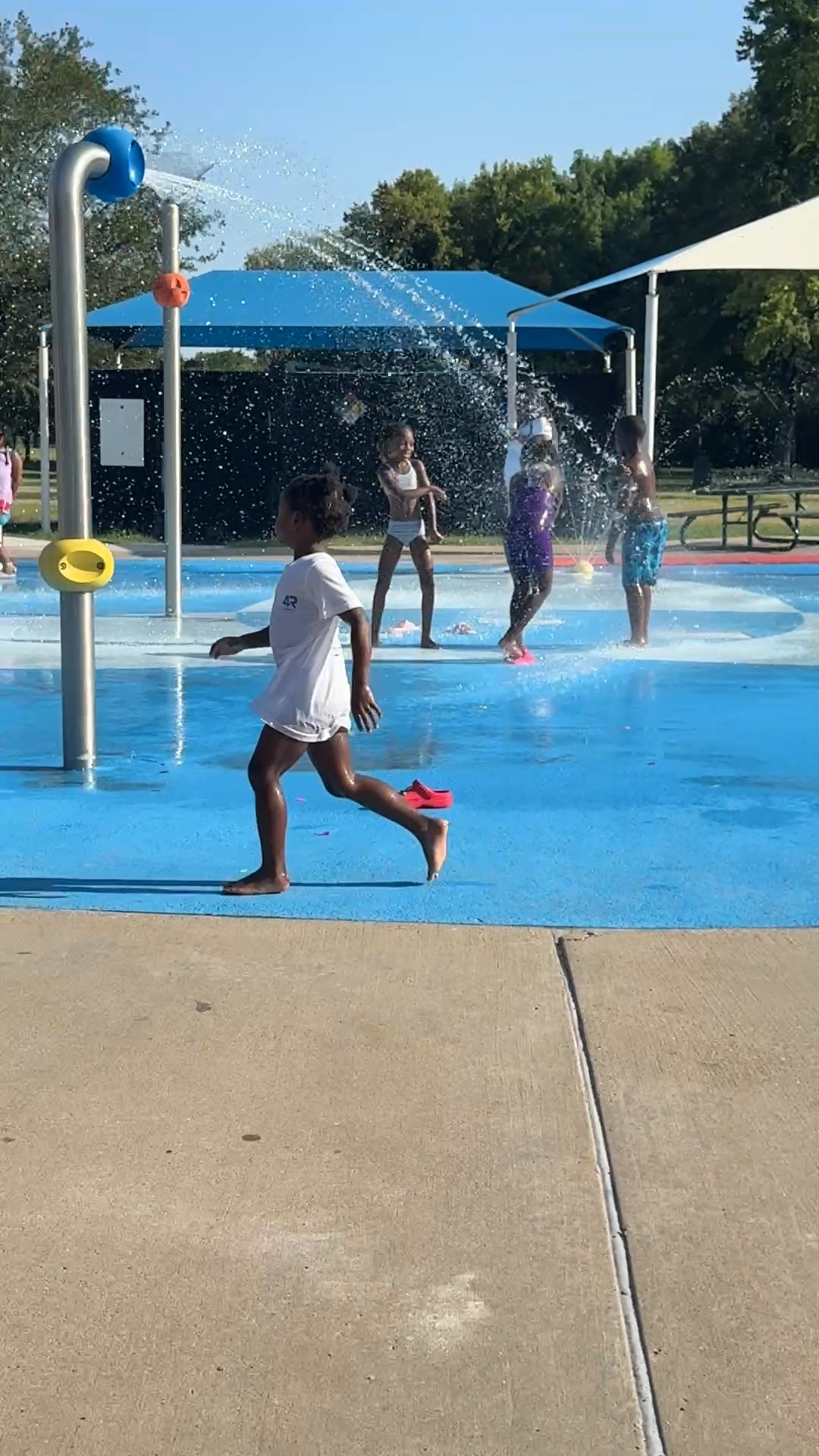 A child in a 4R Legacy t-shirt running through the splash pad at Splash 4 Supplies