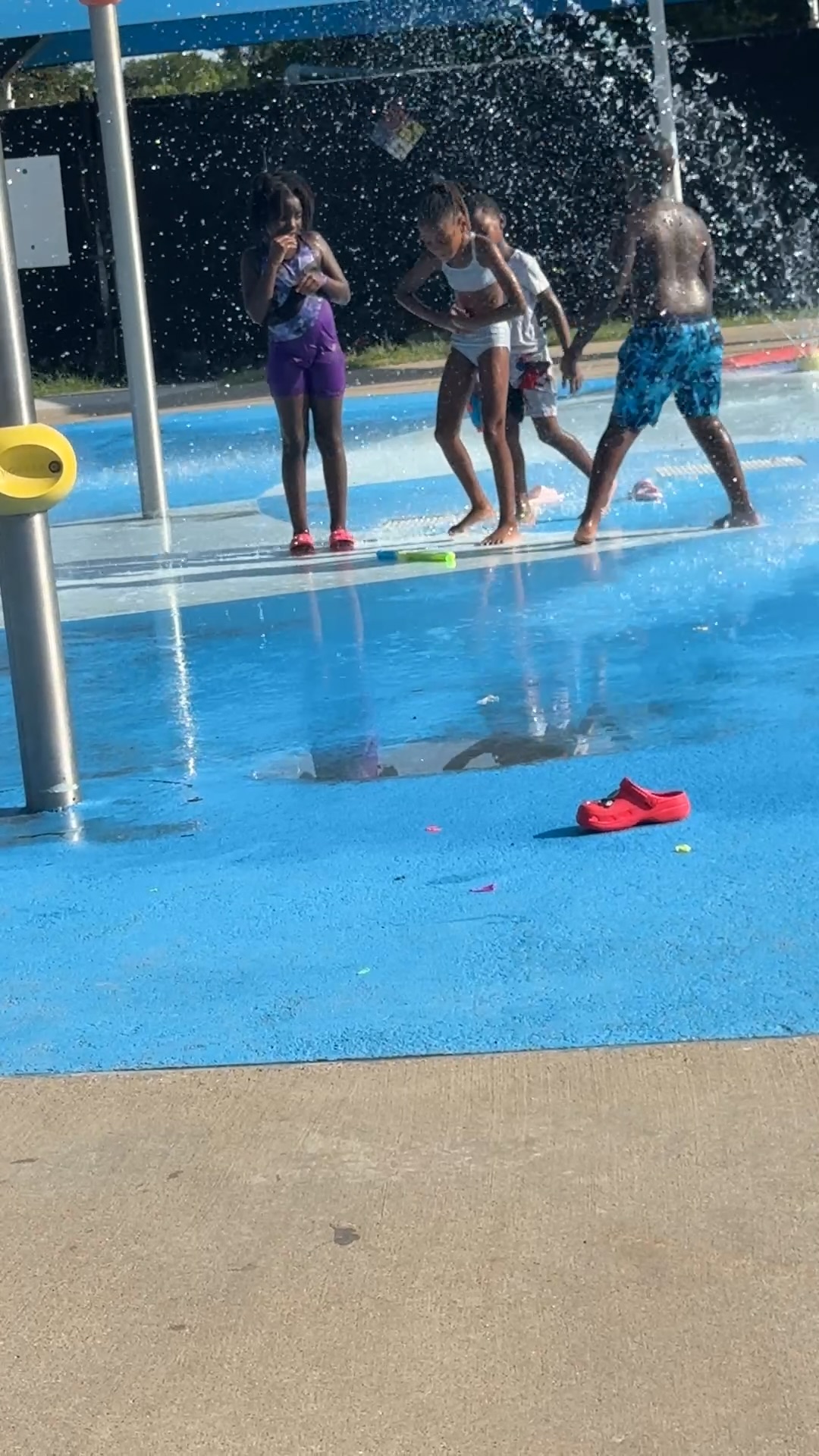 A group of students cooling off together in the splash pad water curtain